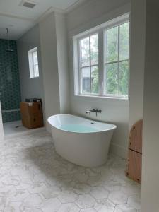 a white bath tub in a bathroom with a window at 2 Abalone Ln, New Construction, Luxury Finishes, Pool, Game Room in Hilton Head Island +65 photos