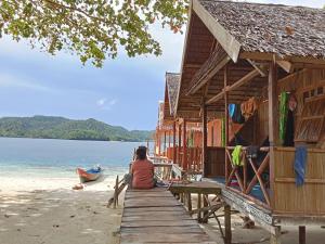 a woman sitting on a dock on a beach at Nyandetor Homestay in Yennanas Besir