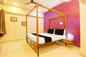una camera con letto a baldacchino e parete rosa di Super Hotel O Jaistambh Chowk Formerly Guru Kirpa a Raipur