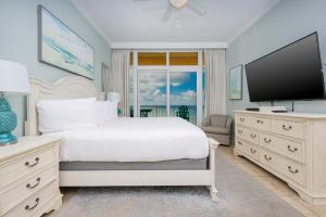 a bedroom with a white bed and a flat screen tv at Phoenix Gulf Shores 2001 condo in Gulf Shores +38 photos