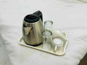 un hervidor de agua y dos vasos en una bandeja en Hotel Shree, en Ujjain