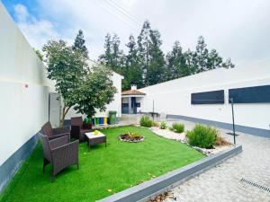 Un patio trasero con césped, sillas y una fogata. en Casa Trevo de 4 Folhas, en Furnas