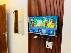 Un televisor de pantalla plana colgado en una pared de madera. en Hotel Shree, en Ujjain