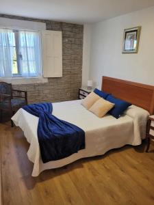 a bedroom with a large bed with blue pillows at GRUPO GONTAD CASA CARMUCHA in Graña