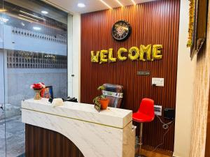 Un cartel de bienvenida en una pared roja con una silla roja. en Hotel Shree, en Ujjain