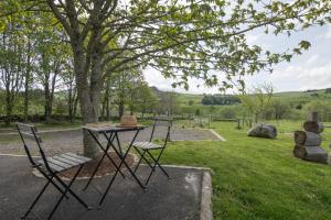 una mesa de picnic con dos sillas y un sombrero. en Chalet du Pradel, en Les Estables