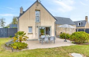 a patio with chairs and an umbrella in front of a house at Maison Proche Mer in Créances