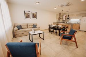 a living room with a couch and tables and a kitchen at Complejo Coirón Premium in San Rafael