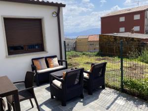 a patio with chairs and a table and a fence at A Casiña de Tivo in Fisterra