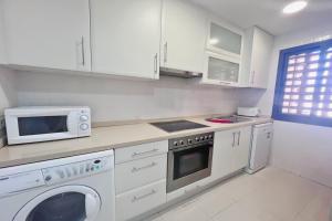 a white kitchen with a microwave and a stove at Paraíso de Roda Golf in Roda