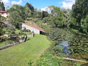 a building next to a river with lilies at La Sérénade des Mauges Charme Nature Détente in Montfaucon