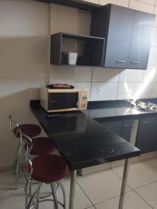 a kitchen with a counter with a microwave and two stools at Apartamento térreo in Bebedouro +9 photos