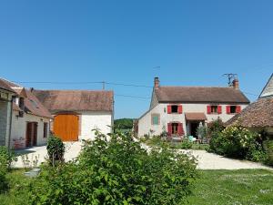 a group of houses with red doors and a yard at Gîte du Rucher in Vimory