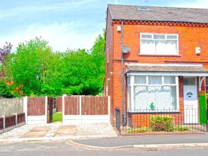 a red brick house with a fence and a gate at Spacious and Comfy Pad - Perfect for Long Stays & Contractors - Close to Sports Village, Leigh Market, and Mesnes Park - Easy Parking - Speedy Wi-Fi - Free On-Site or Nearby Parking - Private Luxury Garden in Leigh