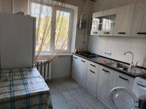 a kitchen with white cabinets and a sink and a window at Квартира в центре Балки, город Тирасполь in Tiraspol