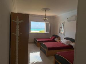 a bedroom with two beds and a view of the ocean at Gorgeous Beachfront House in Sidi Krir in Dawwār Ḩalīs +2 photos