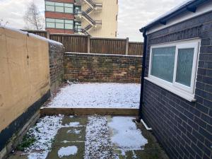 a snow covered yard next to a building with a window at Houghton Guest House in Stoke on Trent
