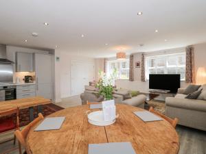 sala de estar con mesa de madera y cocina en The Coach House, en Castle Cary