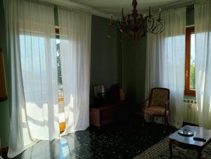 a living room with a chandelier and a chair and a television at Casa Acerbi Quarto Priaruggia in Genoa