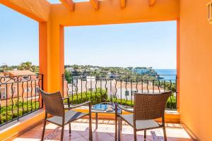 a balcony with two chairs and a table with a view of the beach at Villa Marcolis Mar in Cala Galdana