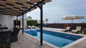 a swimming pool with chairs and an umbrella and a pool at Villa Talya in Peyia