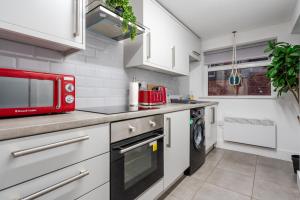 a kitchen with a microwave and a washer and dryer at Anfield Apartments in Liverpool