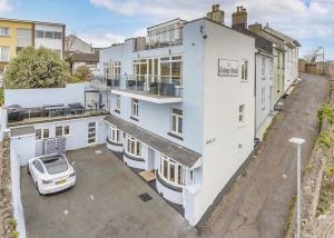 una casa blanca con un coche aparcado en un estacionamiento en Anzac Lookout Central Brixham Retreat with Stunning Views, en Brixham