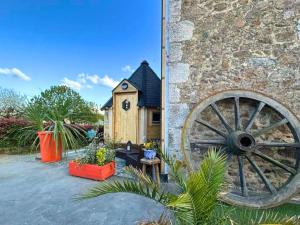 a house with a wooden wheel next to a building at Les Philous Gourmands in LʼÉpaux