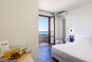 ein Hotelzimmer mit einem Bett und einem Tisch mit einer Obstschale in der Unterkunft Albergo Auralba in San Vito lo Capo + 37 Fotos