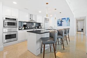 フォート・ローダーデールにあるRitz-Carlton Luxury Oceanview 3-Bedroom Residenceの白いキャビネット付きのキッチン、スツール付きのバー
