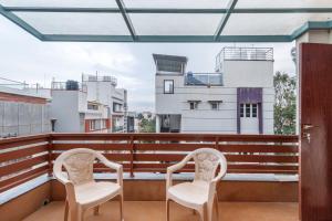 two chairs on a balcony with buildings in the background at Terrastone Duplex Spacious ApartmentNr Lake in Bengaluru