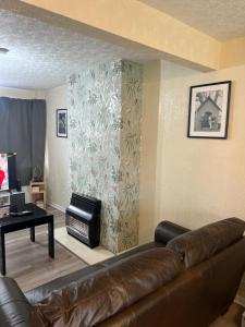ein Wohnzimmer mit einem Ledersofa und einem Tisch in der Unterkunft Five Oaks House- Entire 3 Bedroom House for Family & Contractors with up to 5 sleep- NO PARTIES ALLOWED in Willenhall