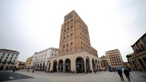 a tall brick building with people walking around it at Loggia Tre Piazze Apartments in Brescia