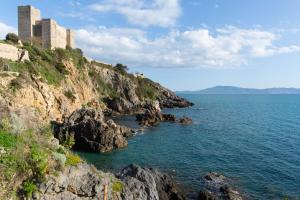 a castle on a cliff next to the ocean at Il Nido di Montiano, giardino, natura e relax in Magliano in Toscana