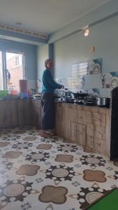 a woman standing in a kitchen preparing food at Udaya Home Stay in Panaoti