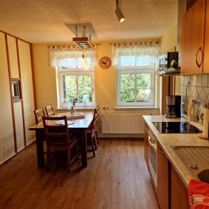 a kitchen with a table and chairs and two windows at Ferienhaus Rumpelt in Kurort Gohrisch