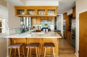 Una cocina con gabinetes de madera y una isla con taburetes de bar. en New Listing The Nautilus Manhattan Beachfront Retreat, en Manhattan Beach
