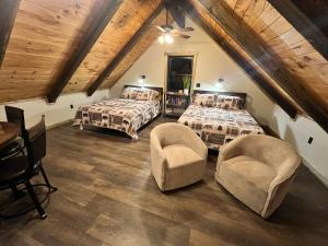 a attic bedroom with two beds and two chairs at Sage Hill Escape in Londonderry