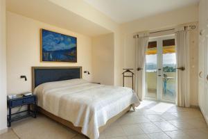a bedroom with a bed and a sliding glass door at Blue Coast Suites - Seaside Retreat with Pool in Exclusive Kommeno in Kommeno