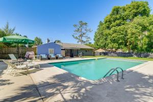 a swimming pool with two chairs and a green umbrella at Old Florida Charm Homosassa Home with Lanai! in Homosassa