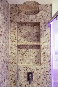 une salle de bain avec un mur en pierre avec une douche dans l'établissement BnB Tirana Centro Balcony, à Tirana