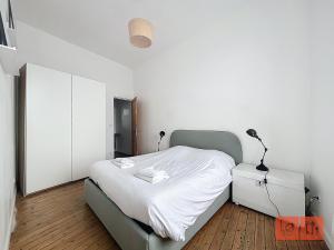 een slaapkamer met een bed en een witte muur bij La parenthèse in Wimereux