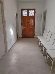 コッレサルヴェッティにあるVillettina con Bagni esclusiviの白い椅子と木製のドアのある部屋