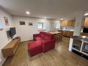 a living room with a red couch and a kitchen at Mountain Chalet in Strembo +1 photo
