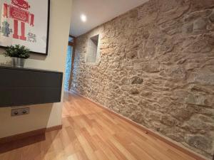 sala de estar con pared de piedra y TV de pantalla plana en Apartamento céntrico O Castelo, en Pobra do Caramiñal 5 fotos más