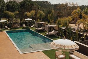 an outdoor swimming pool with chairs and an umbrella at Hotel Leiriartem by Grupo Quinta dos Lagos in Leiria