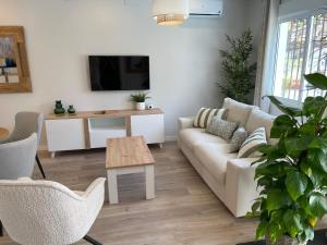 a living room with a white couch and a tv at Casa Pedregalejo in Málaga