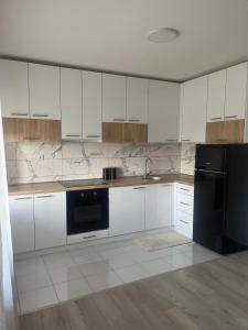 a kitchen with white cabinets and a black refrigerator at Apartmanii Gajić in Kuršumlija