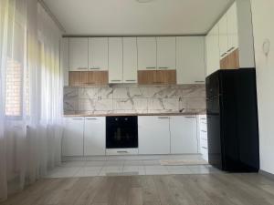 a kitchen with white cabinets and a black refrigerator at Apartmanii Gajić in Kuršumlija