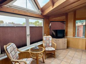 a screened in porch with a tv and chairs at Monteurs- und Ferienwohnung Kahmen in Ahaus